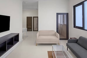A modern living room with a flat-screen TV, a sofa, a coffee table, and a window. - Casa Magnolia Apt 4 | Santurce Multifamily House (San Juan de Puerto Rico)