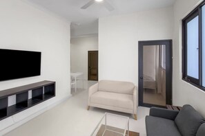 A modern living room with a flat-screen TV, a sofa, a chair, and a coffee table. - Casa Magnolia Apt 4 | Santurce Multifamily House (San Juan de Puerto Rico)