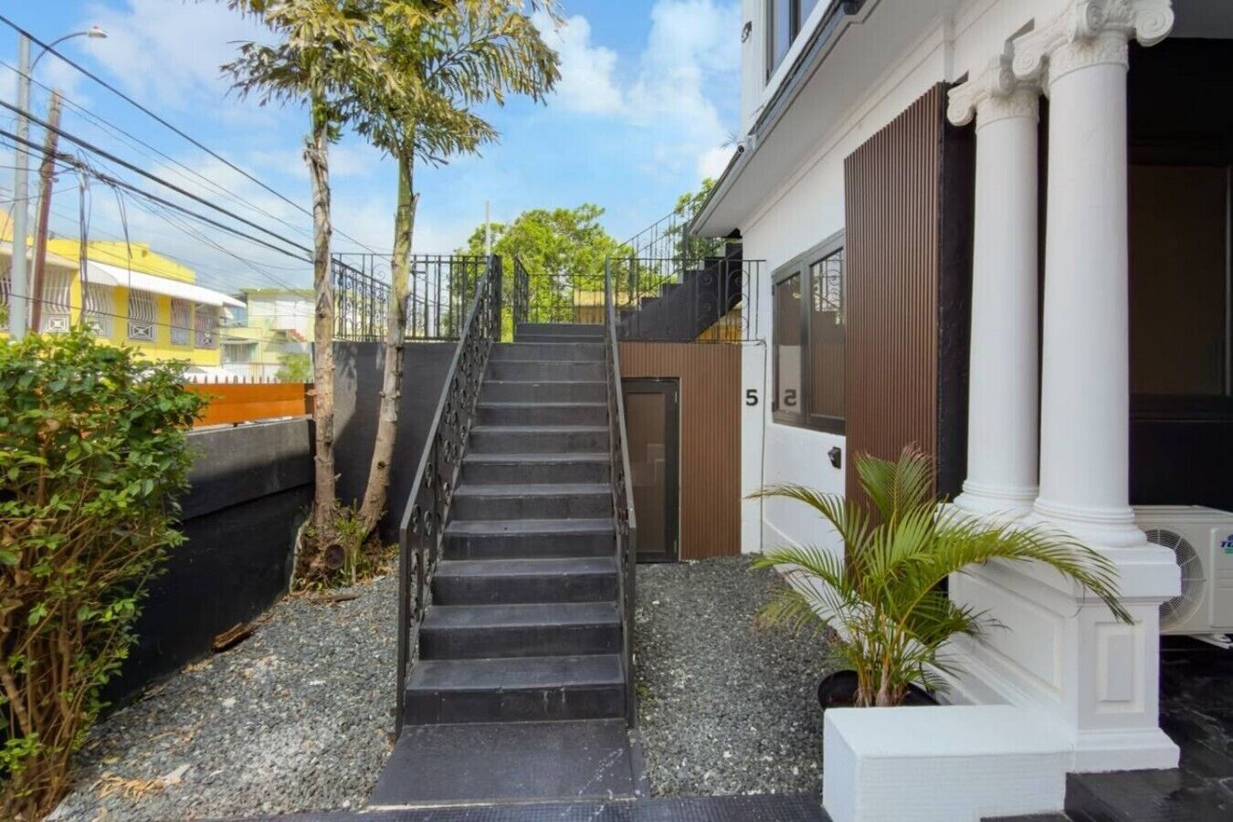 A staircase leading to a building with white columns and a door marked with the number 5.
