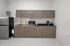 A compact kitchen with a refrigerator, microwave, coffee maker, and a sink. - Casa Magnolia Apt 4 | Santurce Multifamily House (San Juan de Puerto Rico)