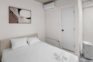 A hotel room with a bed, a door, and an air conditioning unit. - Casa Magnolia Apt 9 | Santurce Multifamily House (San juan de Puerto Rico)