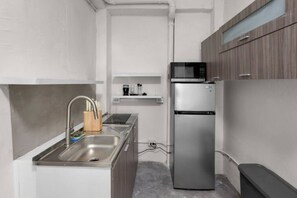 A compact kitchen with a stainless steel sink, a microwave, and a refrigerator. - Casa Magnolia Apt 9 | Santurce Multifamily House (San juan de Puerto Rico)