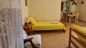Ein Zimmer mit einem Bett, einem Sessel, einem Tisch und einer Essecke.