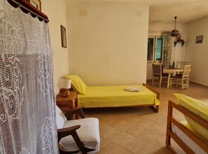Ein Zimmer mit einem Bett, einem Sessel, einem Tisch und einer Essecke.