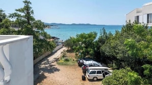 Una propiedad frente al mar con camino de grava, vehículos estacionados y abundante vegetación.