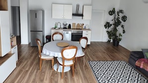Una cocina moderna con armarios blancos, una mesa de comedor con sillas y una planta grande en maceta.