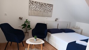 A bedroom with a bed, two chairs, a small table, a potted plant, and a painting on the wall. - Apartment & Rooms Papa - Studio Apartment With Balcony and Partial Sea View (Zupa dubrovacka)