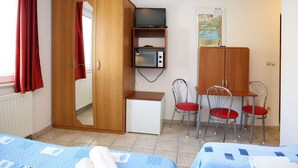 A room with a wardrobe, a television, a microwave, a desk, two chairs, and a bed. - Apartments & Rooms Villa Petra - Double Room (Sibenik)
