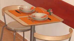 Ruokapöytä, jonka päällä on kaksi kulhoa, veitsi ja haarukka oransseilla aluslautasilla.