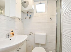 A bathroom with a white sink, toilet, and shower. There is a window above the toilet and a mirror above the sink. - Mobile Homes Bella Vita 2 (Biograd na Moru)