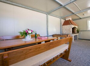 A room with a wooden table, benches, a flower vase, and a stone fireplace. - Mobile Homes Bella Vita 2 (Biograd na Moru)