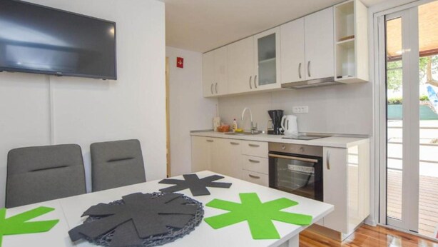 A modern kitchen with white cabinets, a built-in oven, and a large window. - Mobile Homes Bella Vita 2 (Biograd na Moru)