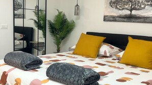 A modern bedroom with a bed, a mirror, a plant, and a painting on the wall. - Apartments Noa Old Town - Studio - Ground Floor (Dubrovnik)