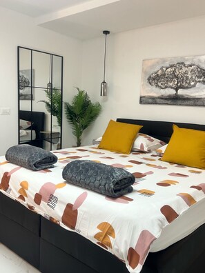 A modern bedroom with a bed, a mirror, a plant, and a painting on the wall. - Apartments Noa Old Town - Studio - Ground Floor (Dubrovnik)