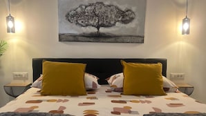 A hotel room with a bed, two bedside lamps, a wall-mounted painting, and a nightstand with a lamp. - Apartments Noa Old Town - Studio - Ground Floor (Dubrovnik)