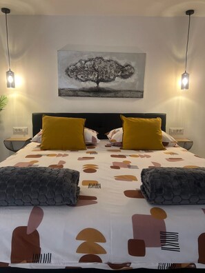 A hotel room with a bed, two bedside lamps, a wall-mounted painting, and a nightstand with a lamp. - Apartments Noa Old Town - Studio - Ground Floor (Dubrovnik)