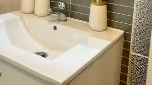 A bathroom with a white sink, a mirror above it, and toiletries on a shelf. - Apartments Noa Old Town - Studio - Ground Floor (Dubrovnik)