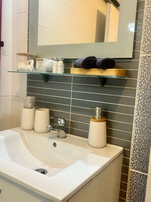 A bathroom with a white sink, a mirror above it, and toiletries on a shelf. - Apartments Noa Old Town - Studio - Ground Floor (Dubrovnik)