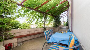 An outdoor patio with a table and chairs, a pergola with vines, and a brick wall. - Apartments Ana &amp; Bogdan - Two Bedroom Apartment With Terrace (Postira)