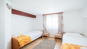 A twin room with two single beds, a wooden nightstand, a small table, and a window with curtains. - Apartments Ana &amp; Bogdan - Two Bedroom Apartment With Terrace (Postira)