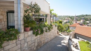 A narrow stone pathway leading to a building with a stone wall and potted plants. - Two Bedroom Apartment With Terrace (Supetar)