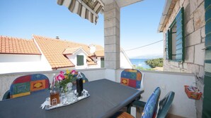 A balcony with a table set for two, overlooking a coastal area with traditional buildings. - Two Bedroom Apartment With Terrace (Supetar)