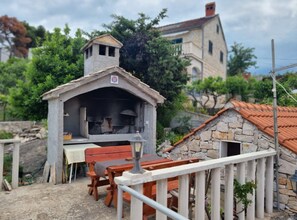 Ein rustikaler Essbereich im Freien mit einer Steinarchitektur, einem Holztisch und Bänken.