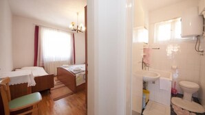 A bedroom with two beds, a wooden floor, a chandelier, and a window with curtains. - Two Bedroom Apartment With Terrace (Supetar)