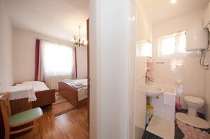 Ein Schlafzimmer mit zwei Betten, Holzboden, einer Kandelaber und einem mit Vorhängen drapierten Fenster.