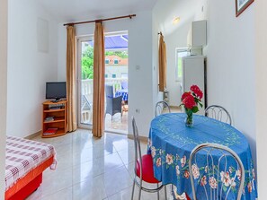 A room with a bed, a TV, a dining table with chairs, and a balcony with a view. - Apartments Ivo - One Bedroom Apartment With Terrace and sea View (Postira)