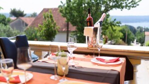 Een eettafel gedekt met borden, glazen en een fles wijn, met uitzicht op een prachtig landschap.