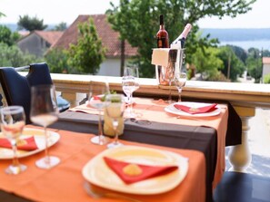 A dining table set with plates, glasses, and a bottle of wine, overlooking a scenic view. - Apartments Milic - Twin Room 1 - 2 (Obrovac)
