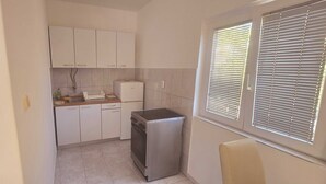 A compact kitchen with white cabinets, a built-in oven, and a small refrigerator. - Apartments Mateo - One Bedroom Apartment - White (Vodice)