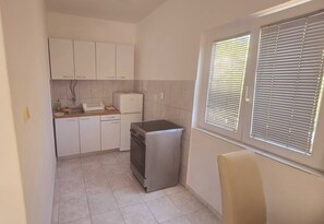 A compact kitchen with white cabinets, a built-in oven, and a small refrigerator. - Apartments Mateo - One Bedroom Apartment - White (Vodice)