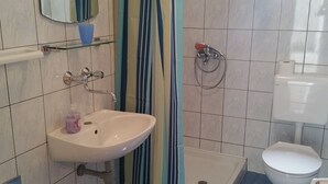 A bathroom with a white sink, a toilet, a shower, and a mirror. - Apartments Mateo - One Bedroom Apartment - White (Vodice)