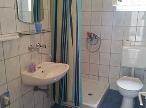A bathroom with a white sink, a toilet, a shower, and a mirror. - Apartments Mateo - One Bedroom Apartment - White (Vodice)