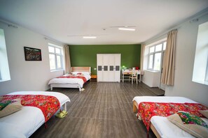 Habitación de hotel con dos camas, un escritorio, un armario y una pared verde.