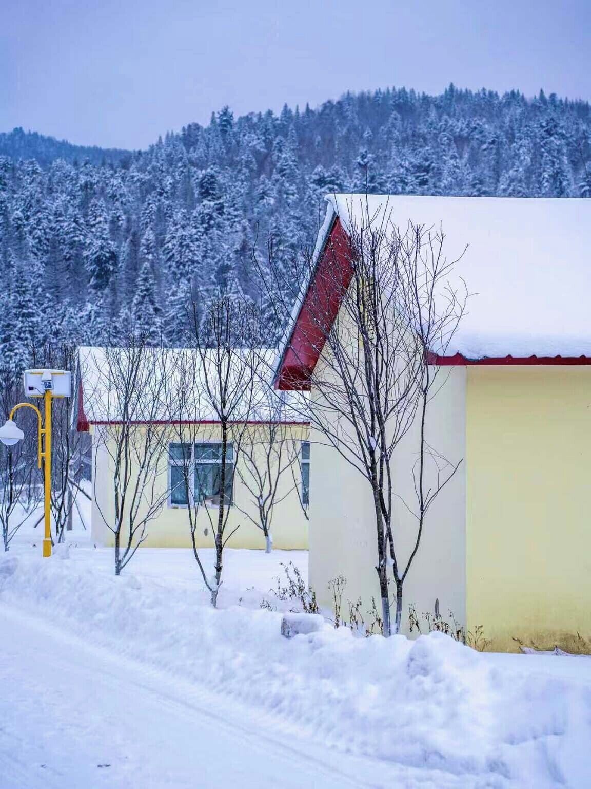A snow-covered landscape with a building featuring a red roof and a yellow facade.