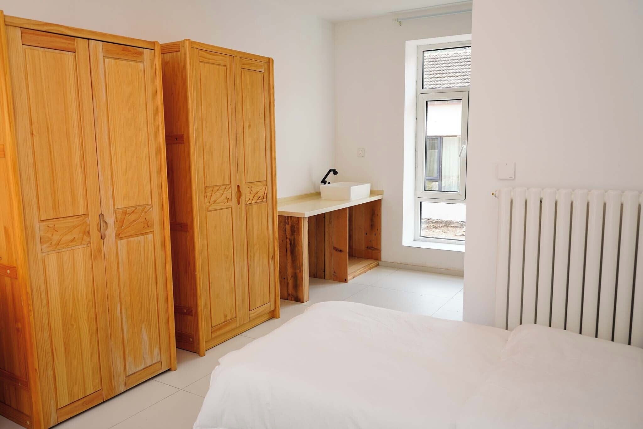 Un dormitorio con cama, escritorio con lavamanos y armario.