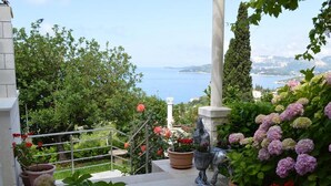 Ein Garten mit Kübelpflanzen, einer Statue und Blick aufs Meer.