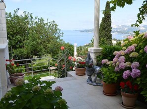 Ein Garten mit Kübelpflanzen, einer Statue und Blick aufs Meer.