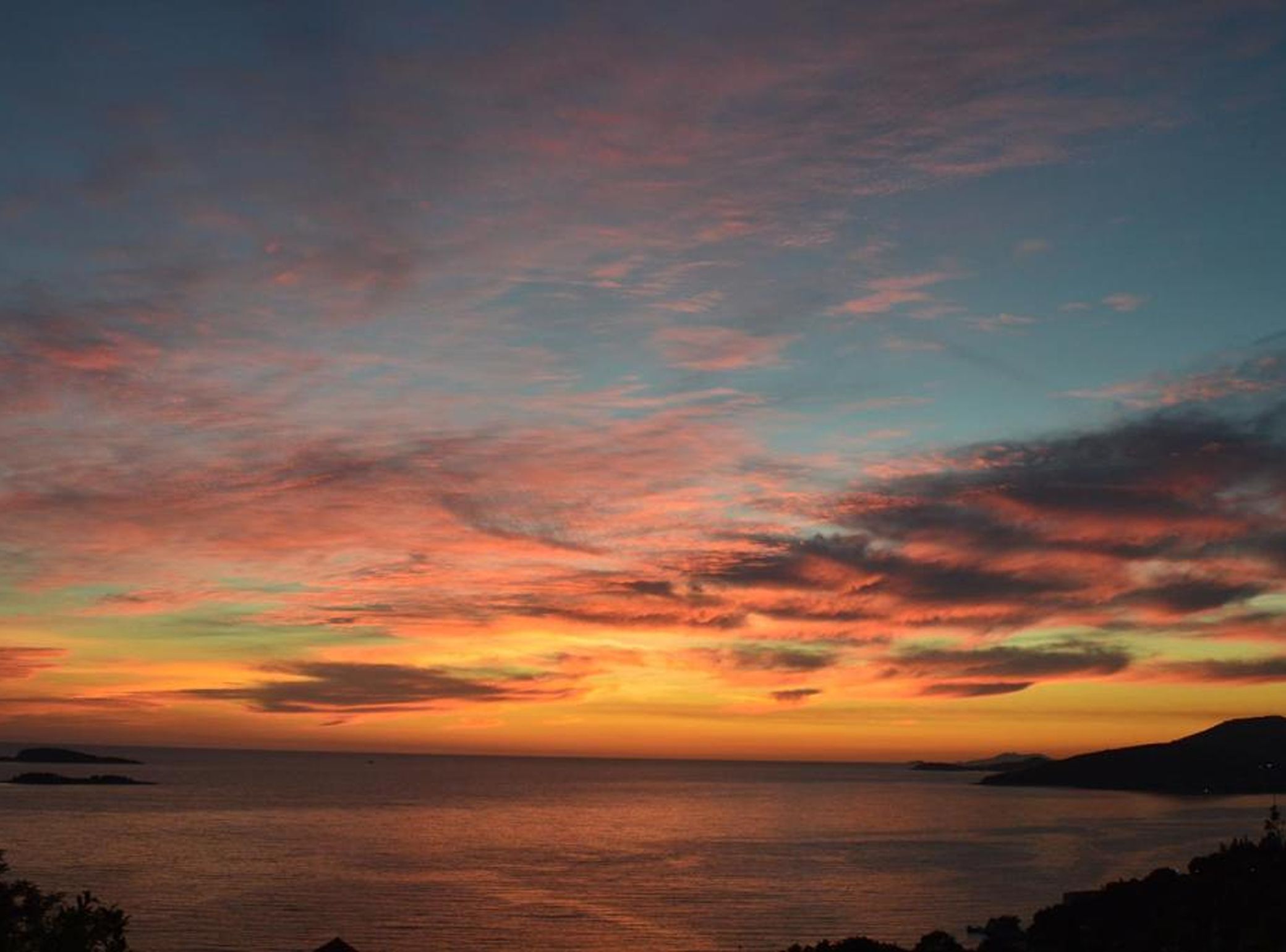 A sunset over a body of water with a distant landmass.