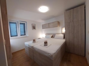 A bedroom with a bed, a wardrobe, a window with blinds, and a ceiling light. - Apartments Spilan (Zupa dubrovacka)