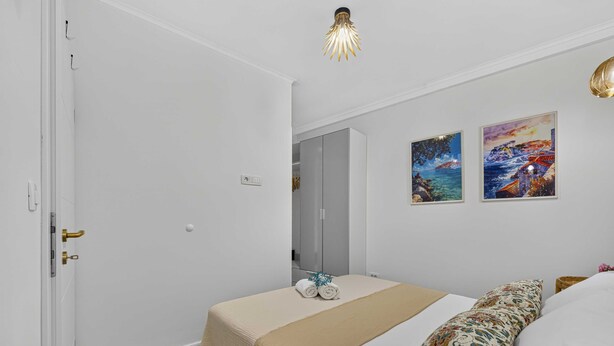 A bedroom with a bed, a bedside table, a wardrobe, and two paintings on the wall. - Sea Escape (Zupa dubrovacka)