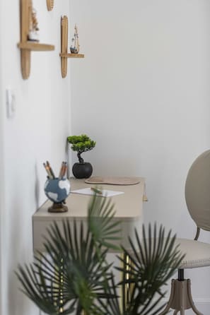 Un escritorio minimalista con un bonzai, un globo terráqueo y una pequeña estantería con adornos.
