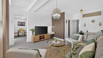 Una sala de estar moderna con una televisión de pantalla plana, una mesa de centro redonda y un sofá.