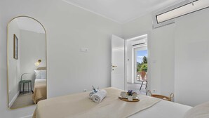 A hotel room with a bed, a mirror, a bedside table with a lamp, a window, and a view of the outdoors. - Sea Escape (Zupa dubrovacka)