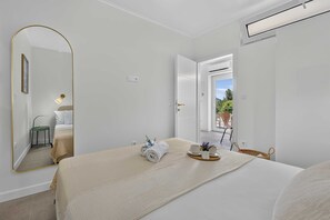 A hotel room with a bed, a mirror, a bedside table with a lamp, a window, and a view of the outdoors. - Sea Escape (Zupa dubrovacka)