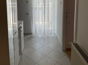 A kitchen with white cabinets, a countertop, and a tiled floor. - Apartmani Meri (Vodice)