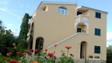 A two-story building with a balcony, arched windows, and a stone foundation.